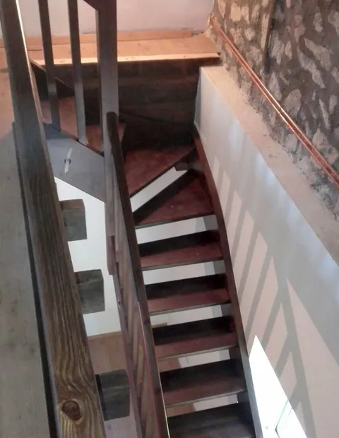 Escalera de madera adosada a un muro de piedra