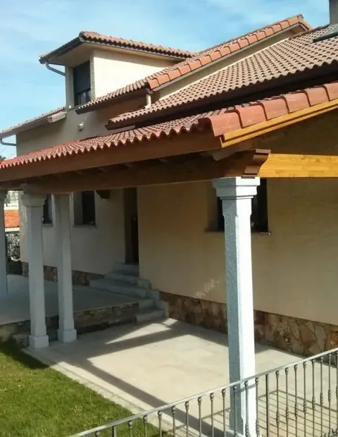 Porche con columnas y alero de madera en la fachada de una vivienda