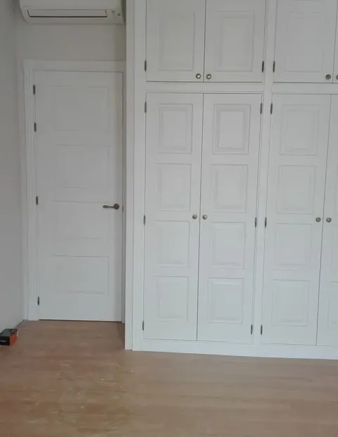 Armario empotrado blanco de cuatro puertas junto a una puerta de paso