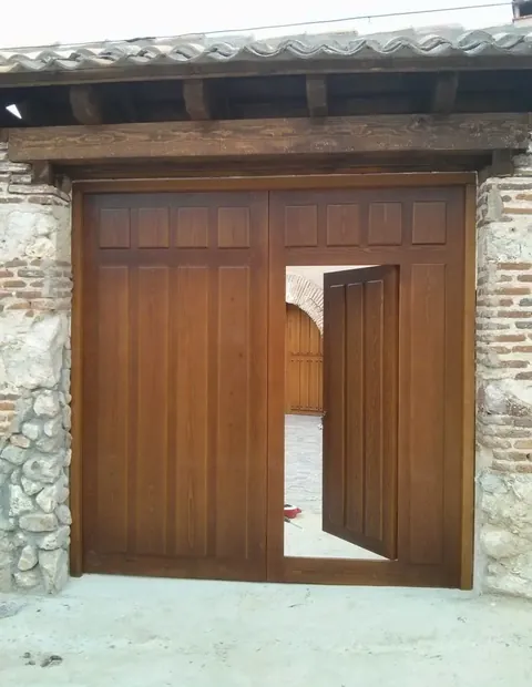 Portón de madera de dos hojas en un muro de piedra y ladrillo
