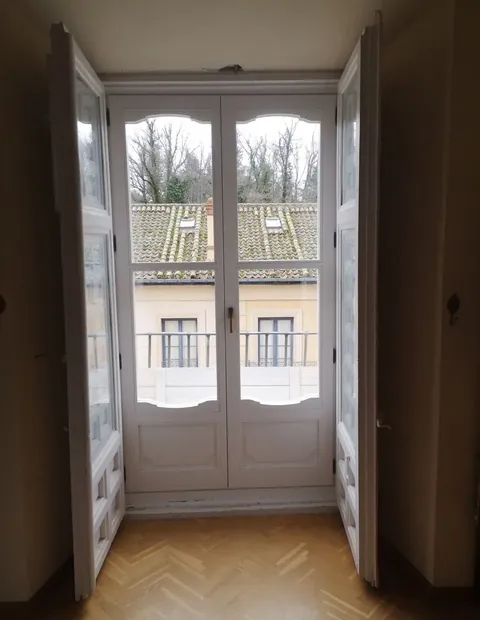 Ventana de dos hojas con contraventanas interiores sobre suelo de espiga