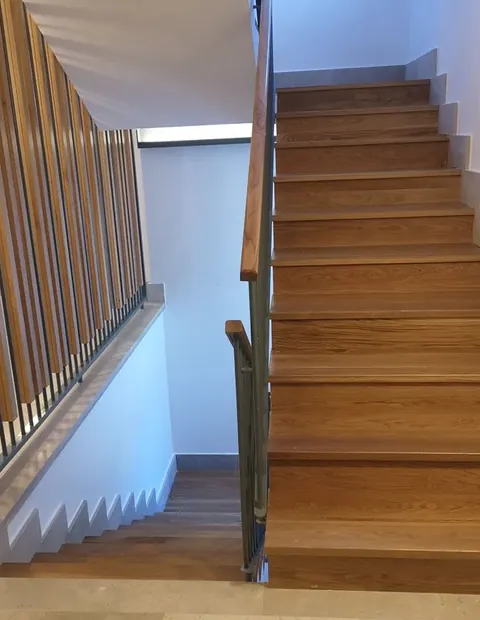 Escalera de madera con barandilla de listones verticales