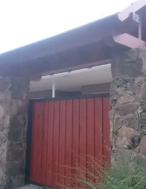 Portón corredero rojo encajado en un muro de piedra