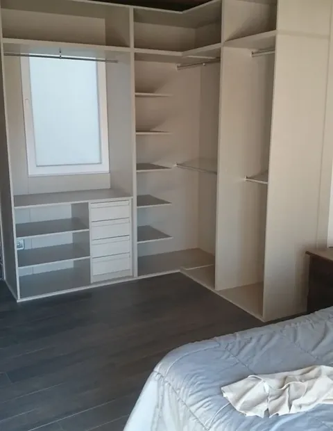 Vestidor abierto con baldas y cajoneras en un dormitorio