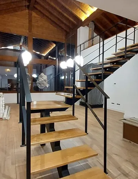 Escalera de peldaños de madera y estructura metálica bajo cubierta de madera
