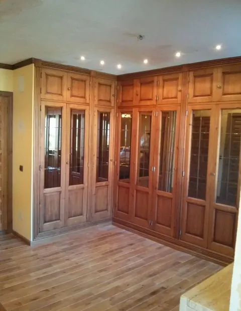 Salón revestido de madera con ventanales y puertas de cuarterones